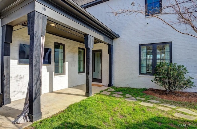 property entrance featuring brick siding and a lawn