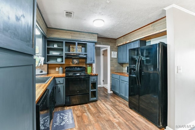 kitchen featuring wood counters, black appliances, light hardwood / wood-style floors, and blue cabinets