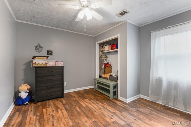 interior space featuring ceiling fan, crown molding, dark wood-type flooring, and a textured ceiling