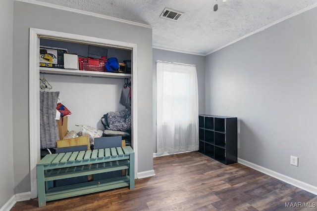 mudroom with dark wood-type flooring, ornamental molding, and a textured ceiling