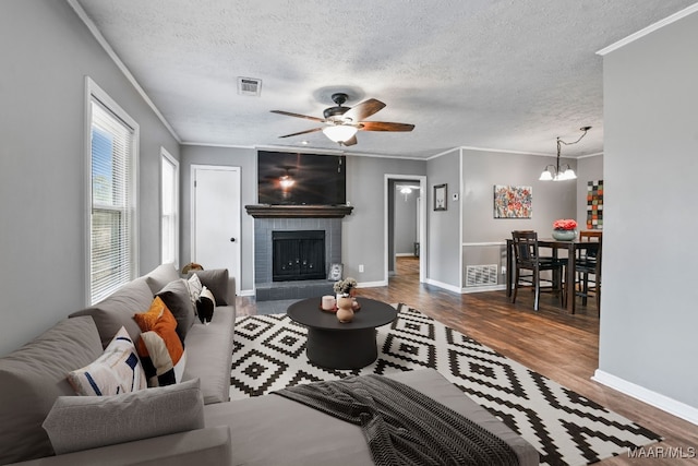 living room with crown molding, dark wood-type flooring, a fireplace, and a textured ceiling