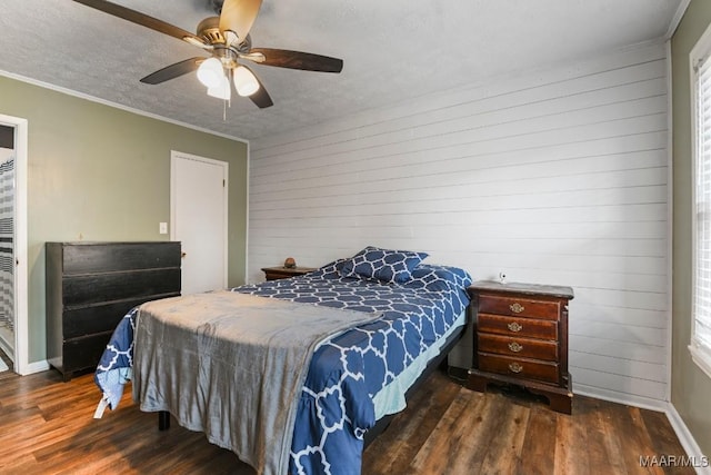 bedroom with ornamental molding, dark wood-type flooring, wooden walls, and a textured ceiling