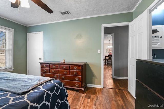 bedroom featuring dark hardwood / wood-style flooring, ceiling fan, ornamental molding, and a textured ceiling