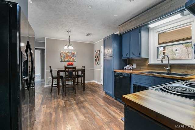 kitchen with pendant lighting, butcher block countertops, sink, black appliances, and blue cabinets