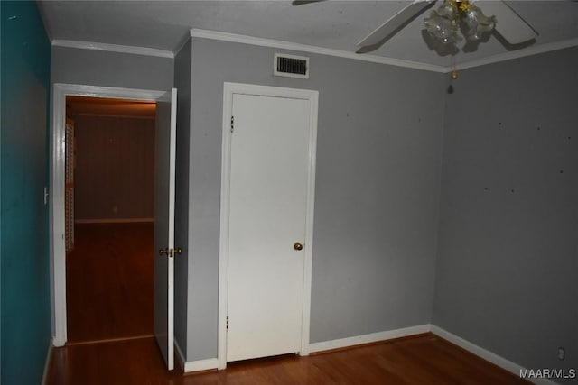 unfurnished bedroom with wood-type flooring, ornamental molding, ceiling fan, and a closet