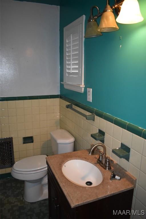 bathroom featuring vanity, tile walls, and toilet