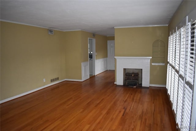 unfurnished living room featuring a brick fireplace, crown molding, and dark wood-type flooring