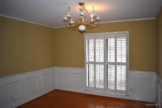 empty room with an inviting chandelier, hardwood / wood-style floors, and crown molding