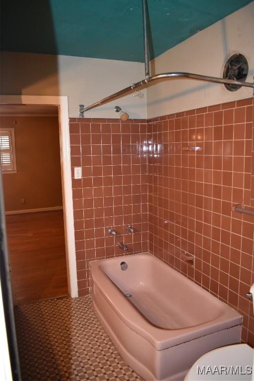 bathroom with tiled shower / bath, tile walls, and toilet