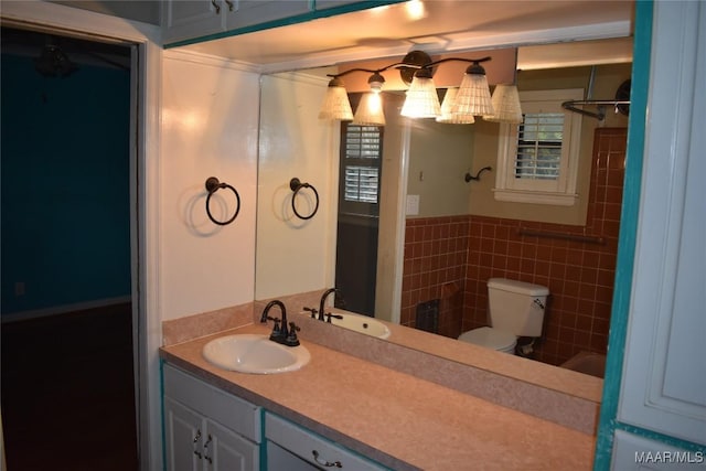 bathroom with vanity, toilet, and tile walls