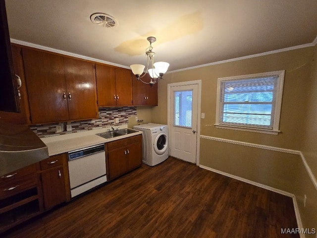 laundry area with dark wood-type flooring, ornamental molding, washer / dryer, and an inviting chandelier