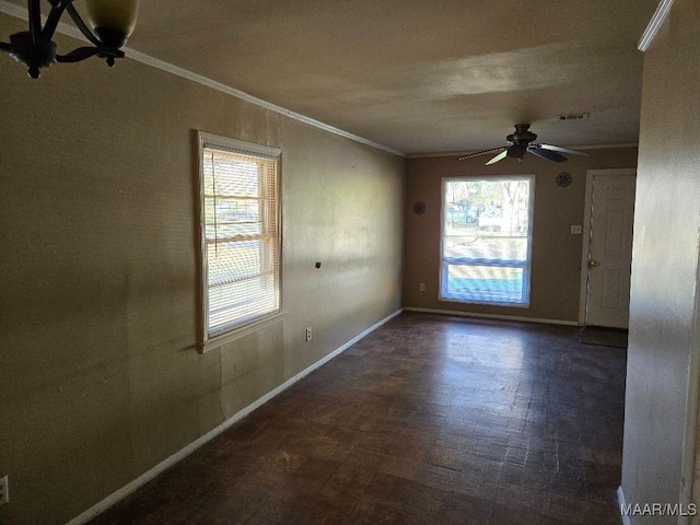 spare room with ornamental molding, visible vents, baseboards, and a ceiling fan