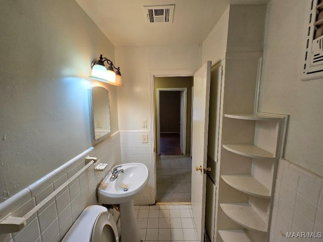 bathroom featuring a wainscoted wall, tile walls, visible vents, toilet, and tile patterned floors