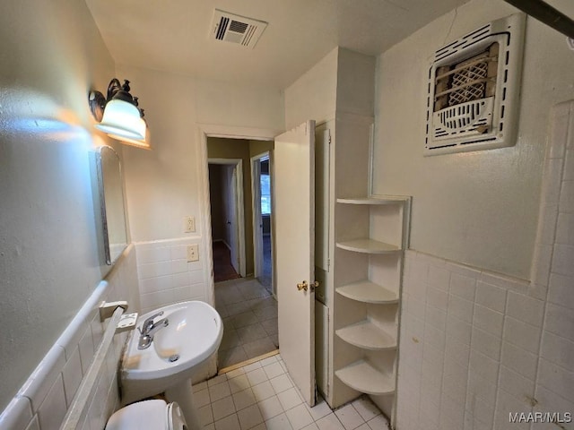 bathroom featuring tile patterned flooring, wainscoting, visible vents, and tile walls