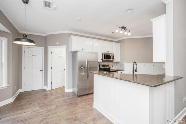 kitchen featuring pendant lighting, dark stone countertops, white cabinets, kitchen peninsula, and stainless steel appliances