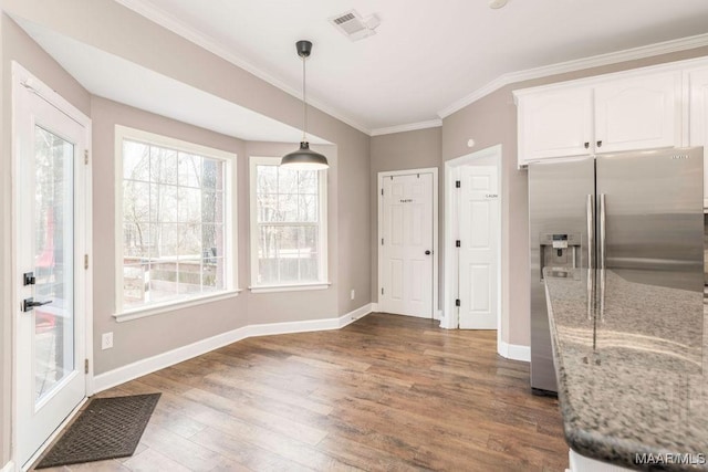 kitchen featuring dark wood-type flooring, light stone counters, hanging light fixtures, stainless steel fridge, and white cabinets