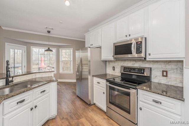 kitchen with sink, dark stone countertops, white cabinets, hanging light fixtures, and stainless steel appliances