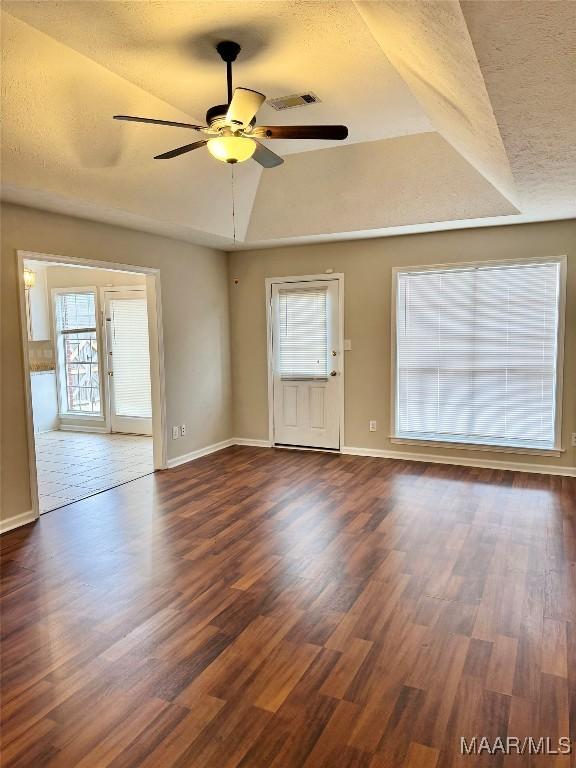 unfurnished room with ceiling fan, lofted ceiling, dark hardwood / wood-style floors, and a textured ceiling