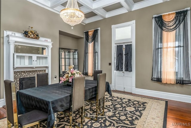 dining space featuring beamed ceiling, wood-type flooring, a chandelier, coffered ceiling, and crown molding