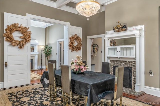 dining space with an inviting chandelier, ornamental molding, a fireplace, and hardwood / wood-style floors