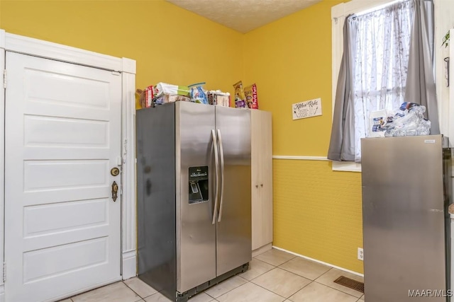 kitchen with light tile patterned flooring, stainless steel fridge, and a textured ceiling