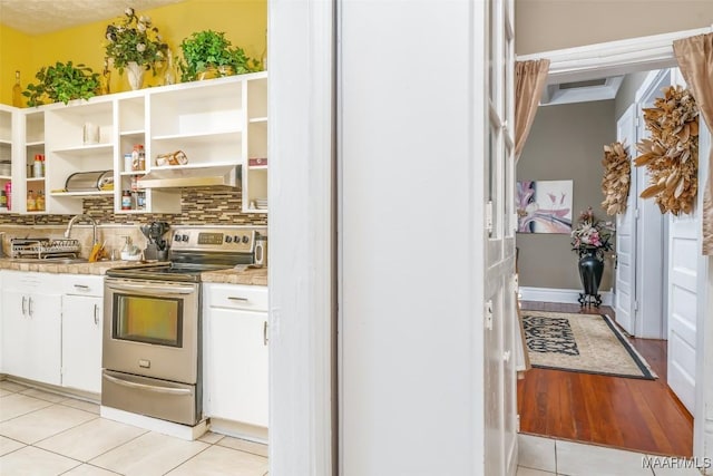 kitchen featuring sink, white cabinetry, light tile patterned floors, electric range, and backsplash