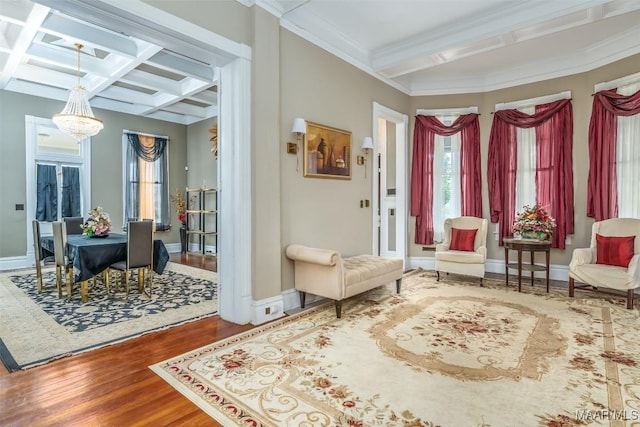 sitting room with hardwood / wood-style floors, beam ceiling, coffered ceiling, a notable chandelier, and ornamental molding