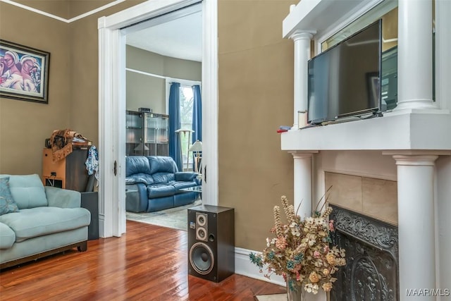 living room featuring hardwood / wood-style floors, a tile fireplace, and ornate columns