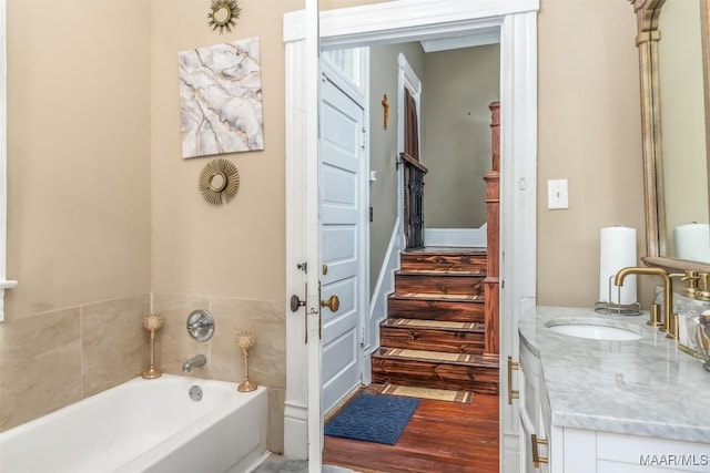 bathroom with vanity, wood-type flooring, and a bath