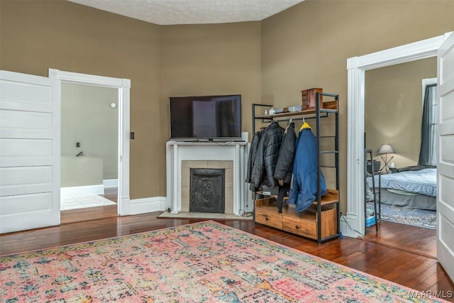 bedroom with a tile fireplace, a textured ceiling, and dark hardwood / wood-style flooring