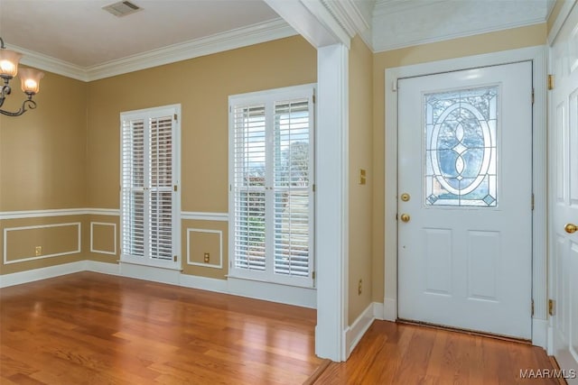 entrance foyer featuring crown molding, wood-type flooring, and an inviting chandelier