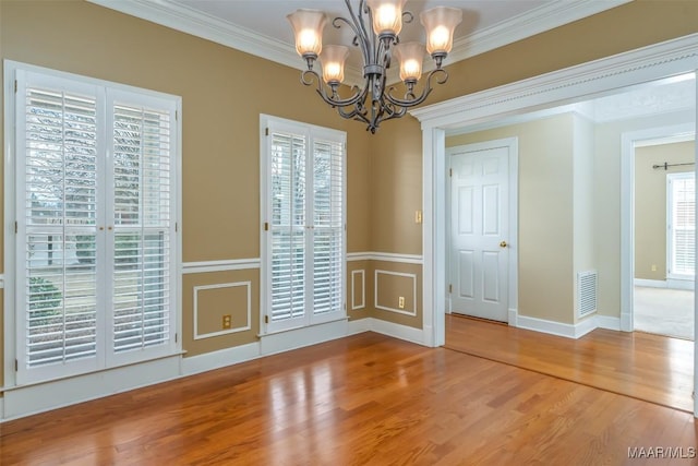 unfurnished dining area featuring crown molding, wood-type flooring, and a chandelier