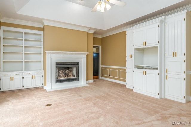 unfurnished living room with ornamental molding, light colored carpet, ceiling fan, and a tray ceiling