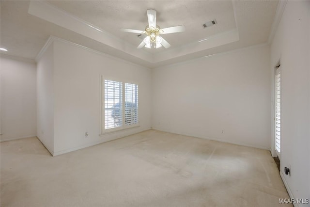 spare room featuring crown molding, a tray ceiling, light colored carpet, and ceiling fan