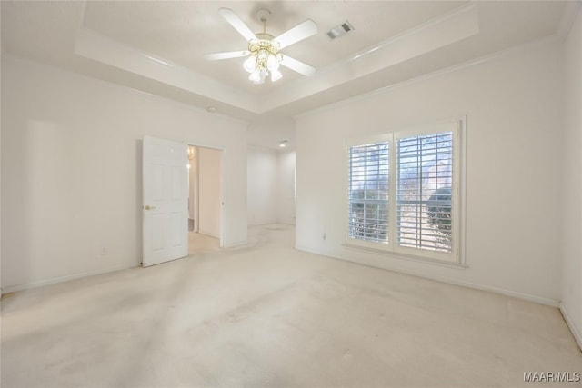 empty room featuring ceiling fan, ornamental molding, a tray ceiling, and light carpet