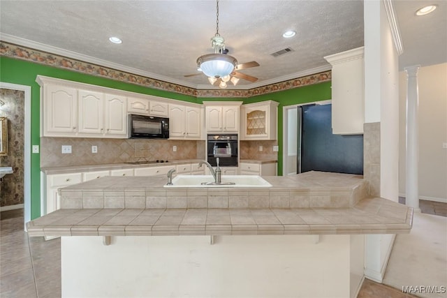 kitchen with white cabinetry, tile countertops, a kitchen breakfast bar, kitchen peninsula, and black appliances