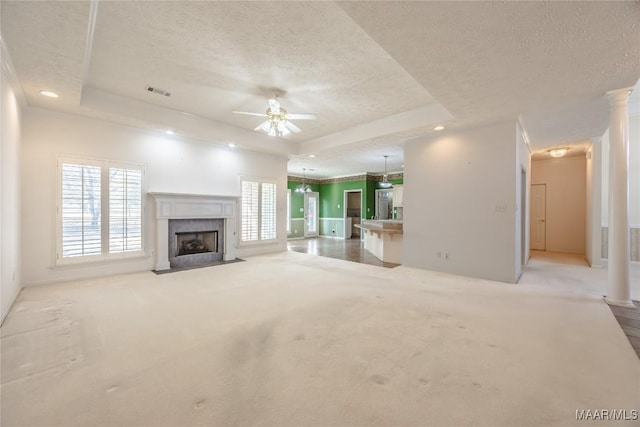 unfurnished living room with a tray ceiling, a high end fireplace, light colored carpet, and a textured ceiling