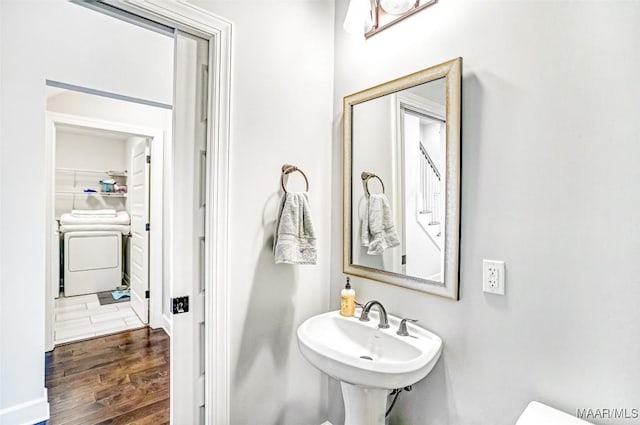 bathroom featuring hardwood / wood-style flooring, washer / dryer, and sink