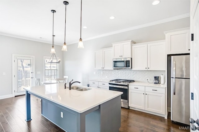 kitchen with sink, appliances with stainless steel finishes, a kitchen island with sink, hanging light fixtures, and white cabinets