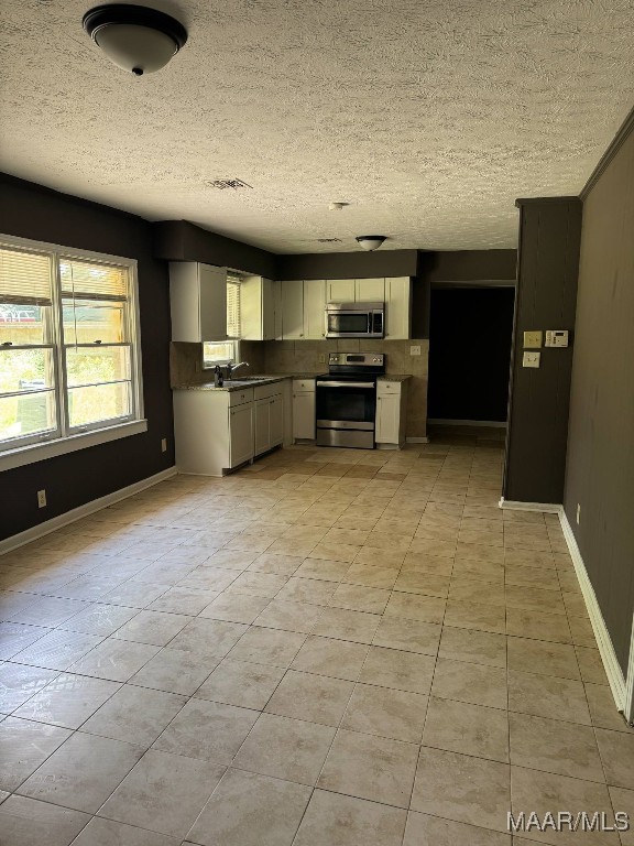 2716 Baldwin Brook Dr, Montgomery, AL 36116 - kitchen featuring stainless steel appliances, a sink, light tile patterned floors, a textured ceiling, and dark countertops