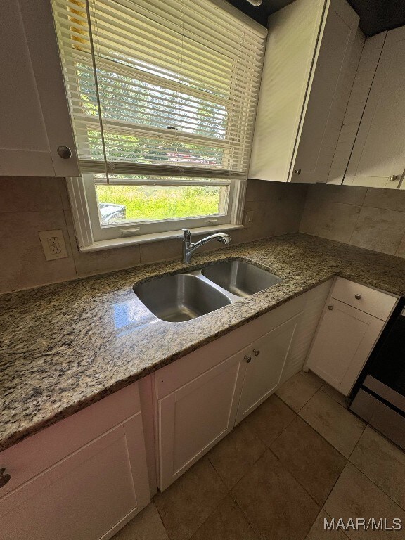 2716 Baldwin Brook Dr, Montgomery, AL 36116 - kitchen with a sink, white cabinetry, tile patterned flooring, light stone countertops, and backsplash