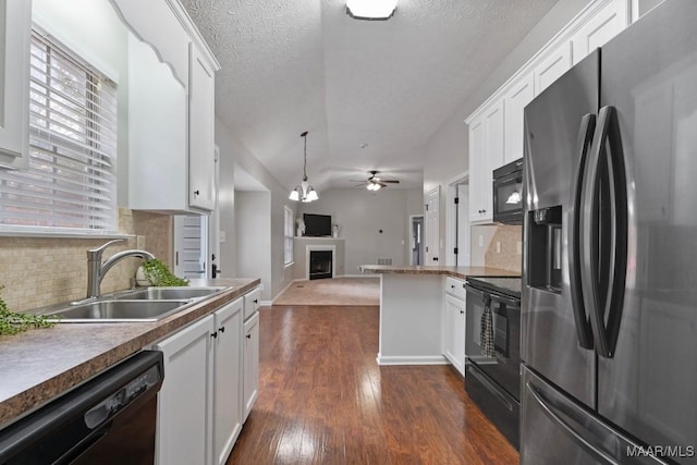 kitchen with hanging light fixtures, sink, white cabinets, and black appliances