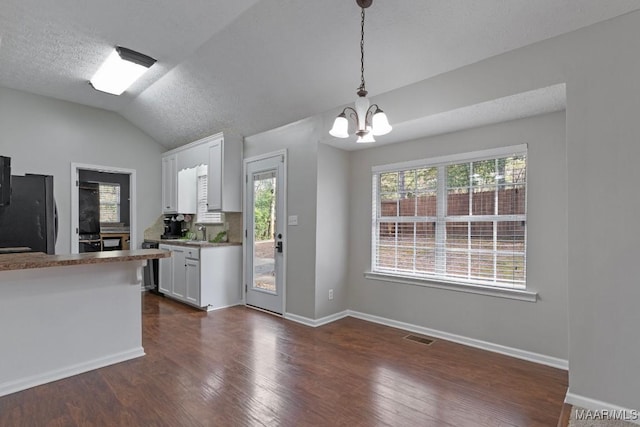 kitchen featuring sink, black refrigerator, dark hardwood / wood-style flooring, pendant lighting, and white cabinets