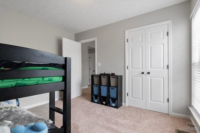 carpeted bedroom with a textured ceiling and a closet