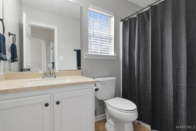 bathroom with tile patterned flooring, vanity, a textured ceiling, and toilet