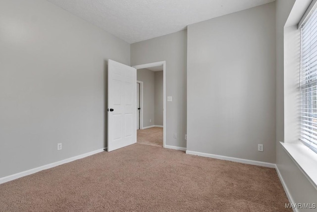 empty room with light colored carpet and a textured ceiling