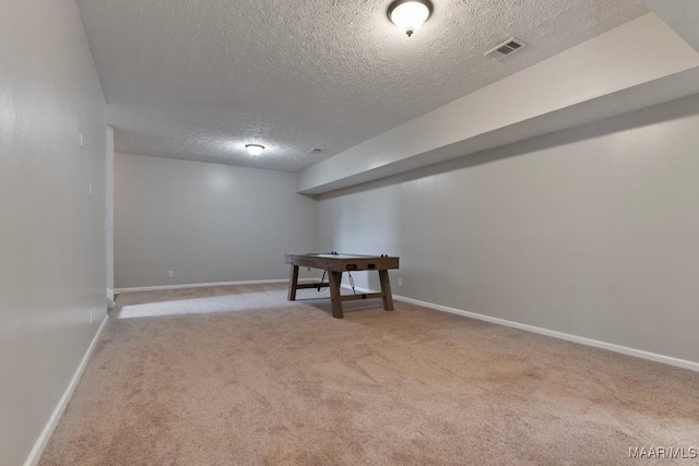 basement featuring light carpet and a textured ceiling