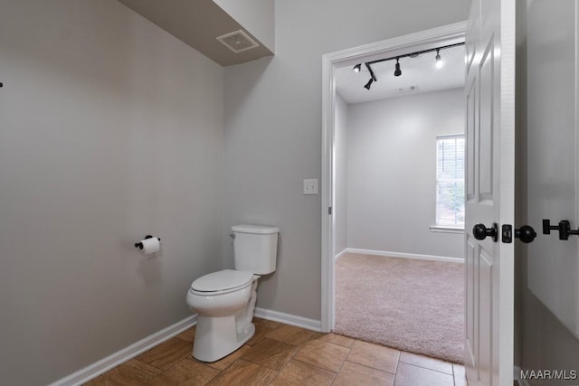 bathroom featuring track lighting and toilet