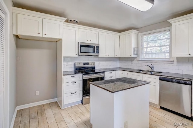 kitchen featuring stainless steel appliances, white cabinetry, a center island, and sink