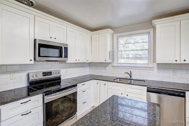 kitchen with sink, stainless steel appliances, dark stone counters, and white cabinets